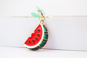 Macro shot of a creative watermelon keychain with red enamel and inlaid black crystals
