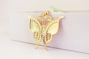 Detailed view of golden butterfly keychain with intricate cutout texture and lobster clasp