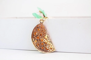 Close-up of golden crescent keychain pendant with stars moon motifs and orange resin inlay