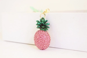 Close-up of pink rhinestone pineapple keychain with gold lobster clasp and green leaf detail