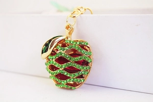 Close-up of green rhinestone apple keychain with gold metal frame and red inner core