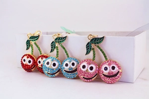 Vue détaillée des porte-clés cerise en strass brillants avec visages souriants colorés