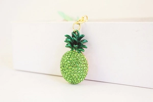 Detail shot of a sparkling green rhinestone pineapple keychain with a golden lobster clasp