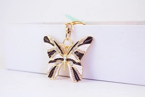 Detailed close-up of a golden butterfly keychain featuring rhinestones and enamel wings