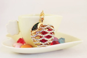 Detail of apple-shaped gold keychain with white rhinestones and green leaf decor