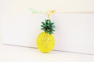 Close-up of sparkling yellow rhinestone pineapple keychain with green leaf metal top