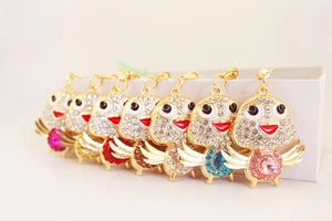 Macro view of crystal chicken keychains with colorful gemstones and gold-tone metal hooks