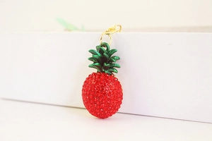 Detail of red rhinestone pineapple keychain with green leaves and gold metal ring