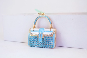Detailaufnahme des blauen Handtaschen-Anhängers mit Strasssteinen und Goldlegierung