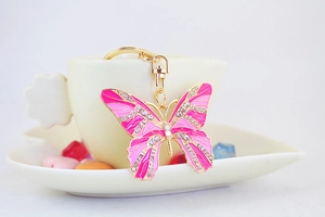 Close-up of pink rhinestone butterfly keychain hanging on a ceramic cup edge