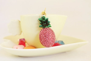 Close-up of pink rhinestone pineapple keychain hanging on a white porcelain cup