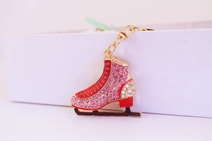 Close-up of pink rhinestone ice skate keychain with golden lobster clasp on white box