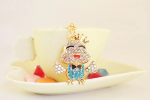 Dettaglio del portachiavi a pulcino con strass e corona appeso al bordo di una tazza