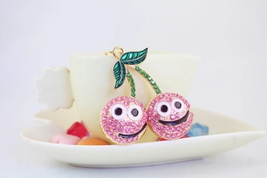 Détail du porte-clés cerise en strass rose avec visage souriant sur une tasse à café