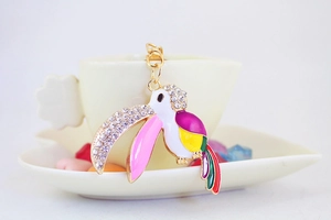 Macro shot of colorful rhinestone toucan keychain with enamel details on a white cup