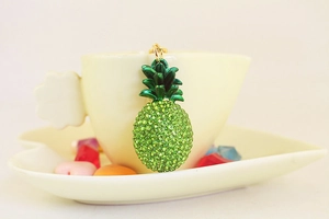 Macro detail of pineapple keychain with green crystals on a yellow coffee cup