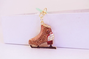 Close-up of golden ice skate keychain with amber rhinestones and black blade