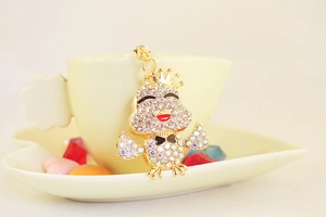 Dettaglio portachiavi pulcino dorato con strass e corona appeso a una tazzina