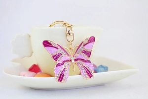 Detail of purple rhinestone butterfly keychain hanging on a white ceramic cup edge