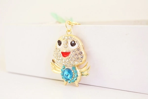 Macro detail of a crystal-encrusted chick keychain with a blue faceted gemstone center