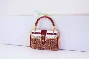 Detail eines rot-weißen Handtaschen-Anhängers mit Strasssteinen und goldener Fassung