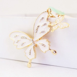 Elegant gold butterfly keychain with white enamel and sparkling rhinestones on white base