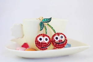 Détail d'un pendentif cerise en cristal rouge avec visages cartoon sur une tasse