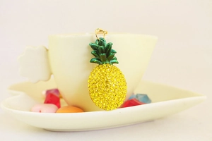Close-up of sparkling yellow rhinestone pineapple keychain on a yellow coffee cup