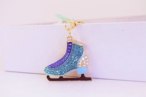 Detail of blue rhinestone ice skate keychain with golden metal ring and enamel decor