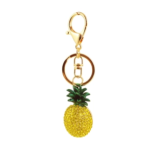 Close-up of golden pineapple keychain with green leaves and sparkling yellow rhinestones