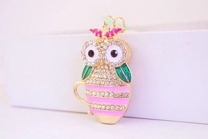 Close-up of owl keychain with sparkling rhinestones and pink bow on gold metal base