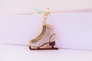 Detailed view of rhinestone-encrusted ice skate keychain with golden metal finish