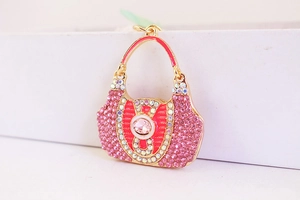 Macro detail of golden metal handbag keychain with pink crystals and red enamel