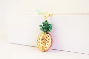 Detailed side view of golden pineapple keychain with pink rhinestones and heart cut-outs
