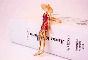 Detail view of fashion doll keychain with red dress and handbag on book background