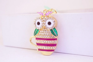 Macro detail of owl pendant with green enamel wings and clear crystal rhinestones