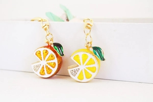 Close-up of lemon and orange keychain pendants with glittering rhinestones and enamel leaves