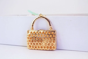 Detail eines goldenen Handtaschen-Anhängers mit Hohlblumenmuster aus polierter Legierung