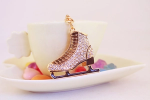 Close-up of golden ice skate keychain featuring sparkling rhinestones and black enamel detail