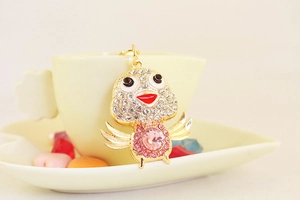 Macro detail of a sparkling golden chick keychain featuring pink crystal and rhinestone inlay