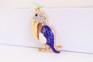 Détail macro du porte-clés toucan avec émail bleu et ornements en strass de cristal