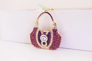 Close-up of cute purple handbag keychain with sparkling rhinestones and golden frame