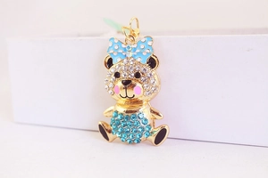 Macro view of a gold-plated bear keychain with blue rhinestones and a polka dot bow