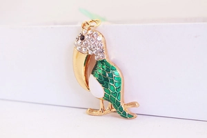 Détail du pendentif toucan doré avec émail vert et cristaux blancs étincelants