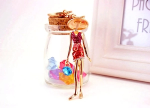 Detail of creative girl doll keychain featuring red rhinestone dress and blue gem accent