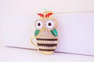 Detail of owl keychain with sparkling rhinestones and green enamel wings in gold setting