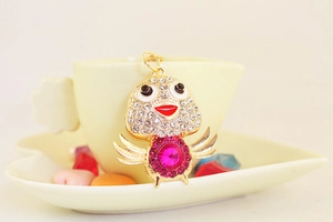 Macro detail of cartoon bird keychain with pink crystal and sparkling white rhinestones