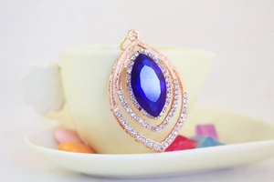 Detailed macro view of marquee shaped blue crystal pendant on a decorative coffee cup