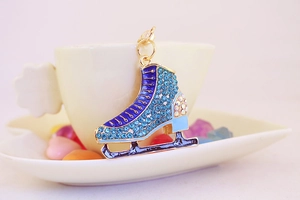 Detail of blue rhinestone ice skate keychain with gold clasp on white coffee cup