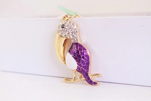Détail du porte-clés toucan avec strass blancs, bec doré et finition émail violet